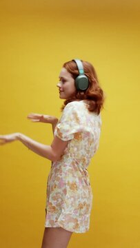 A young ginger white woman wearing headphones dancing  having a good time enjoying the music