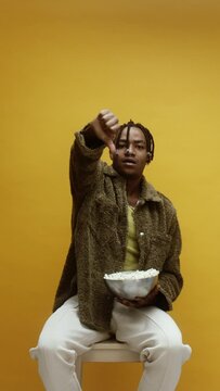 A young stylish black man booing and throwing popcorn