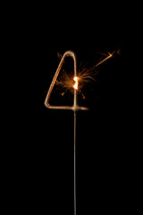 Burning golden sparkler in shape of number four, digit 4, isolated on black background