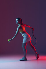 Fototapeta na wymiar Full length portrait of young woman playing tennis isolated on dark background in neon. Healthy lifestyle, fitness, sport, exercise concept.