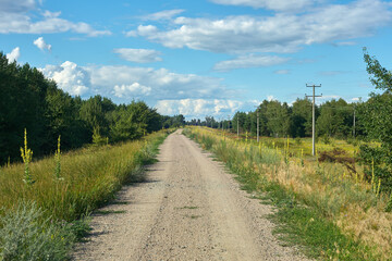 Fototapeta na wymiar Scenic landscape with gravel road and blue sky with clouds.