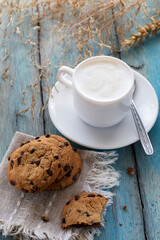 Chocolate chip cookies and a cup of latte on a blue wooden table