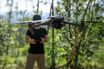 People remote control a flying drone in summer forest