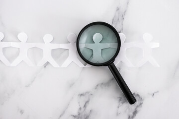 staff shortages and hiring personnel, paper people chain with magnifying glass analysing them