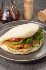 bao bun with breaded chicken and vegetables on a gray plate
