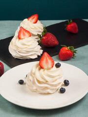 Pavlova - a delicate dessert decorated with strawberries and blueberries