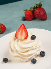 Pavlova - a delicate dessert decorated with strawberries and blueberries