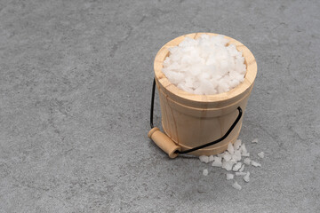 Sea salt in wooden bucket on stone texture background