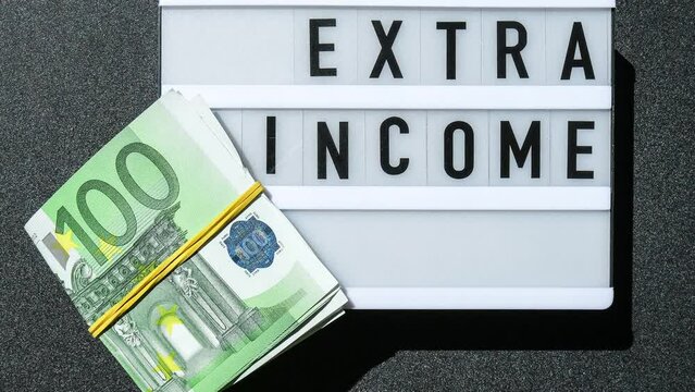 4k zoom in out Lightbox board with word EXTRA INCOME in black letters around euro banknotes. Money, Business, finance, investment, saving. Cash bill. Business budget of wealth and prosperity finance