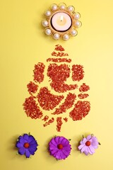 Ganesha art is made with colored rice. Ganesh Chaturthi wallpaper or banner. Ganpati face over yellow background along with diya and flowers. copy space. 