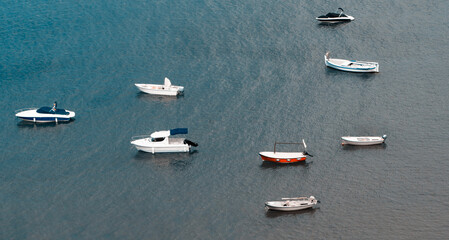 many old fishing boats float in the sea moored with anchors near the shore. Old water transport on the background of the resort town.