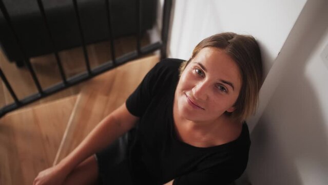 Smiling young adult european woman looking at camera sitting at home enjoying ordinary life.