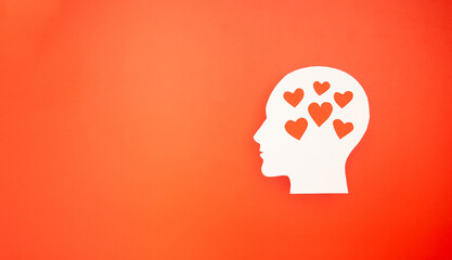 Top view of a white head with a red heart made from paper on a red background