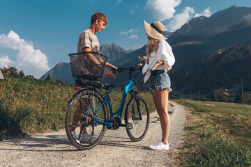 Two friends are cycling along the road. Sport and active life sunset time concept. Couple learning to ride a bike, having fun together, traveling in the mountains in the city