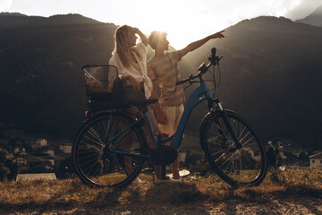 Two friends are cycling along the road. Sport and active life sunset time concept. Couple learning...