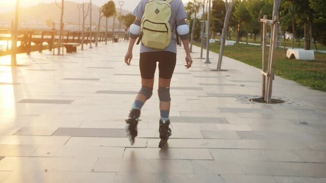 Woman rollerblade on. Young athletic woman rollerblading quickly rides through the park.