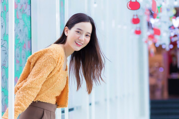 Asian beautiful woman with long hair wears yellow coat and smile happily. in the theme to celebrate Christmas and Happy New Year