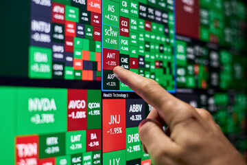 A trader points his finger at one of the stocks on a stock heatmap
