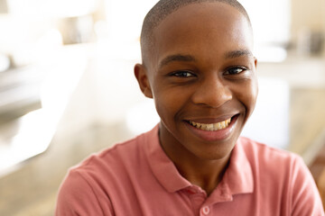 Portrait of happy african american male teenager in kitchen