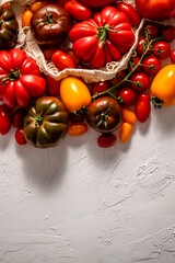 Fresh, raw and colorful tomatoes of different sizes and kinds in eco net bag