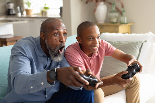Happy african american male teenager with his father playing video games