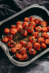 Baking tray with roasted cherry tomatoes with garlic, olive and thyme