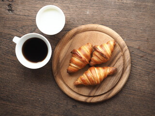 croissant and coffee set on wooden plate