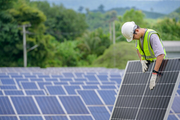 Male engineer wearing a white hard hat Work on checking solar panels and installing solar cells. At photovoltaic power stations working on industrial solar energy storage.