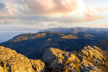 Fototapeta premium amazing mountain landscape of beautiful cloudy sunset above rocks , blue sea and isles with a rock on foreground