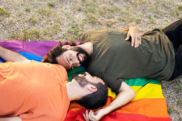Gay couple embracing and showing their love with rainbow flag. LGBT community.