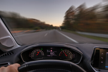 Obraz na płótnie Canvas Driver view to the speedometer at 150 kmh or 150 mph and the road blurred in motion, night fall view from inside a car of driver POV of the road landscape.