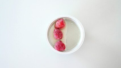 A portion yoghurt with frozen strawberries for diet on a white background