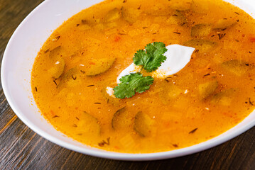 Soup with pickled cucumbers and pearl barley in white plate
