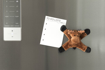 To-do list with empty space for text on the refrigerator door with a funny refrigerator magnet that looks like a stuffed animal donkey