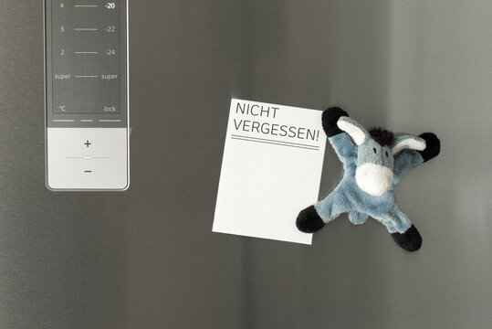 Notiz an der K&uuml;hlschrankt&uuml;r als Erinnerung mit einem lustigen K&uuml;hlschrankmagneten befestigt, der wie ein Stofftieresel ausssieht
