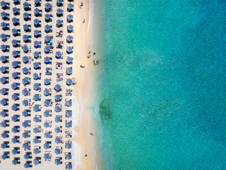 Aerial top down view of the symmetreical rows of sun umbrellas at the turquoise sea of Elia Beach, Mykonos island, Greece - obrazy, fototapety, plakaty