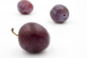 Ripe dark purple plums on a white background.