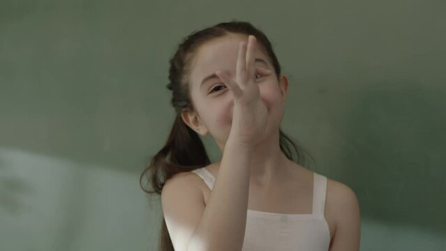 Little girl having fun, making fun by putting her hands on her nose. Thumb to nose, teasing, moving fingers, gestures of humiliation or defiance, making silly faces, crazy expressions.