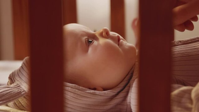 Close up hands father playing with cute charming newborn little baby lying in cradle smiling looking on daddy. Parentheses. Child. Slow motion