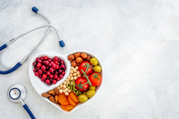 Cholesterol diet concept. Healthy food in heart shaped dish with stethoscope