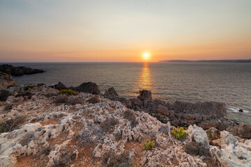 A colourful sunset over the cliffs of Paradis bay in Malta with a view on the Island of Gozo in the...