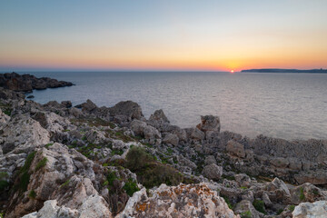 A colourful sunset over the cliffs of Paradis bay in Malta with a view on the Island of Gozo in the Mediterranean Sea. In summer the countries around the Mediterranean enjoy every evening these sunset