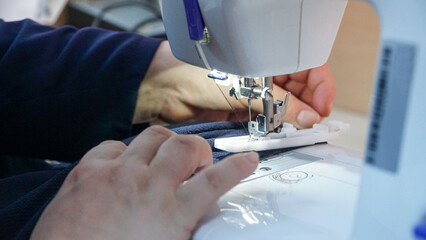 Obraz na płótnie Canvas old woman sewing fabric on machine