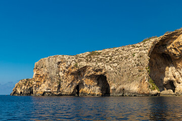 Fototapeta na wymiar The Blue Grotto is a complex of sea caves along the Southeastern part of Malta, and on sunny days, the reflection of sunlight on the white sandy seafloor lights up the caves in bright blue hues