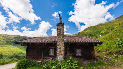 Holzhaus oder Hütte in den Zilltertaler Alpen mit grüner Berglandschaft und blauem Himmel im Hintergrund, Österreich im Sommer