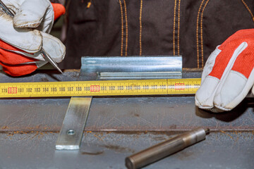 Markings on a metal surface for drilling holes. The worker uses a tool to measure and mark on an iron surface.