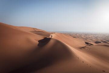 Fototapeta na wymiar Man on top of a huge red desert dune