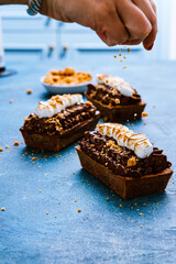 Smores cakes on blue being sprinkled with graham cracker crumbs