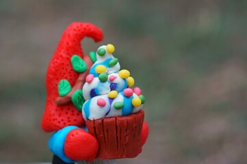 Naklejka premium A figure of a dwarf with a cupcake in his hand.