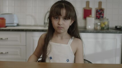 Little girl angry, angry and disobedient at bad behavior showing middle finger. In the kitchen, the middle finger points badly and asks not to be disturbed. Provocation and rude attitude.
